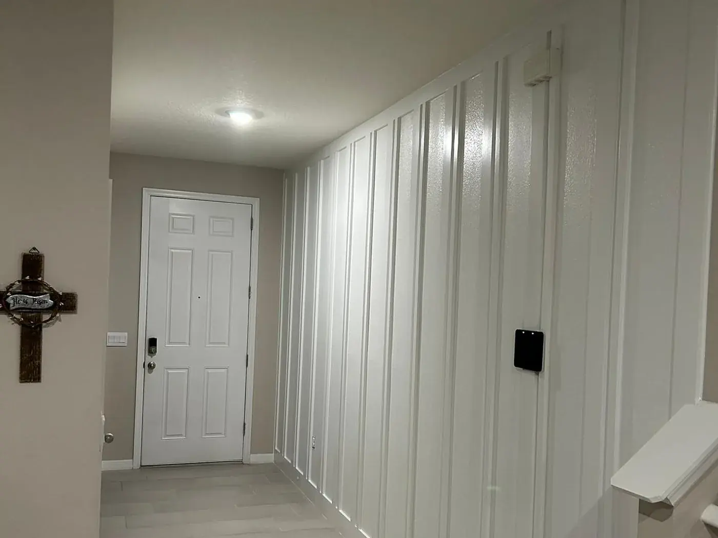 Hallway with a white board and batten accent wall running to the front door