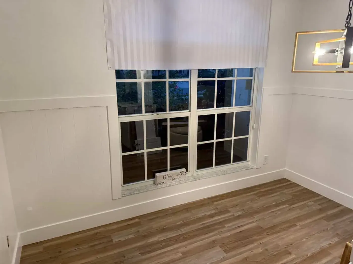 Dining room with white panelled wainscoting running under a divided light window