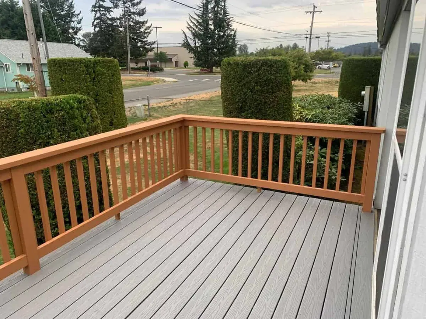 The same deck finished, cedar toned railing against grey composite boards