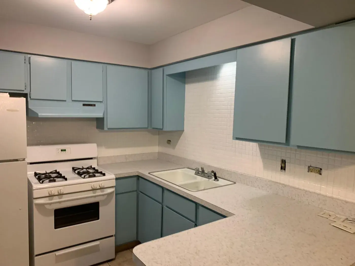The same kitchen after refinishing, cabinets in a clean soft blue