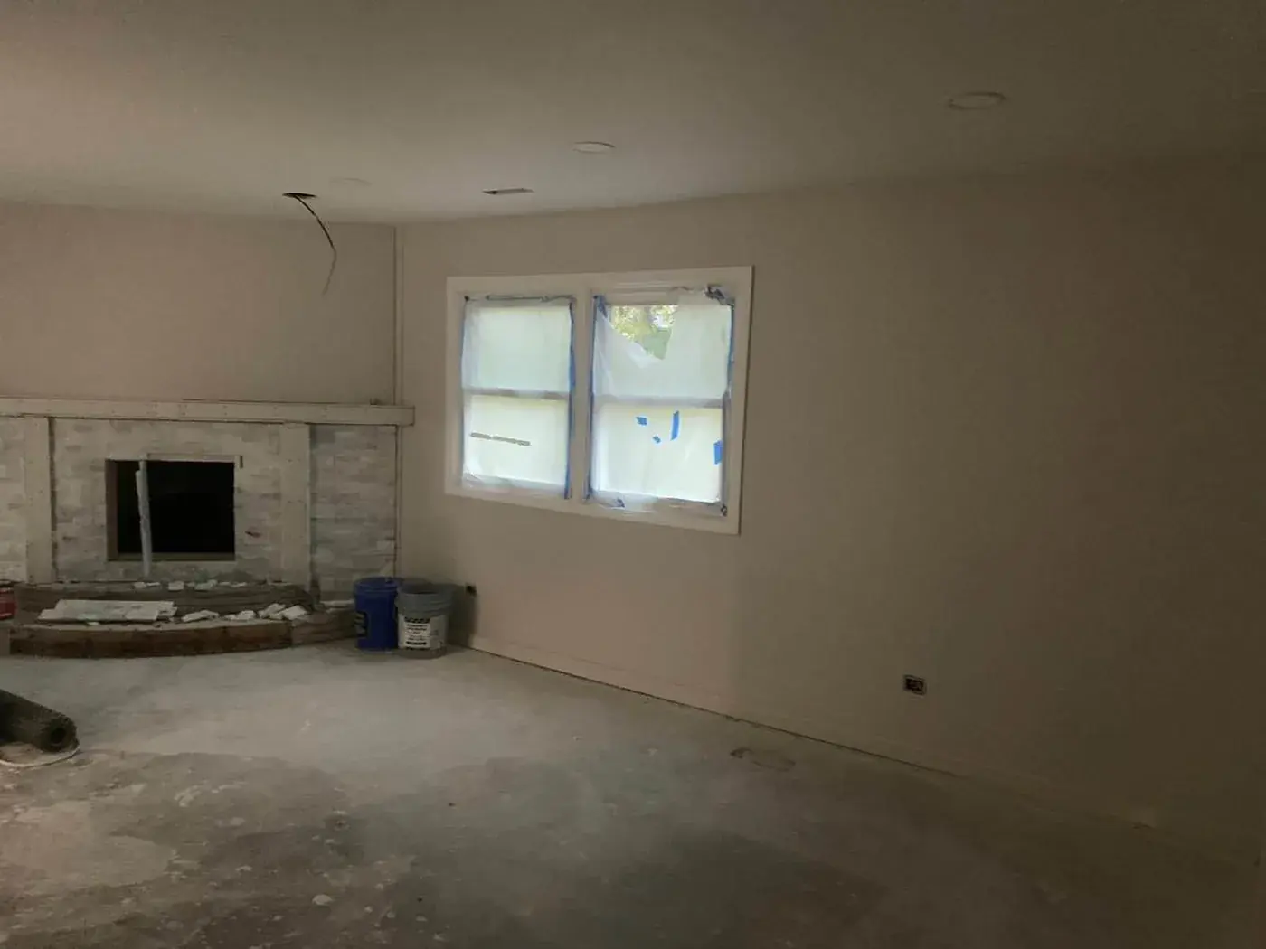 Living room stripped back to the slab, stone fireplace waiting for its surround