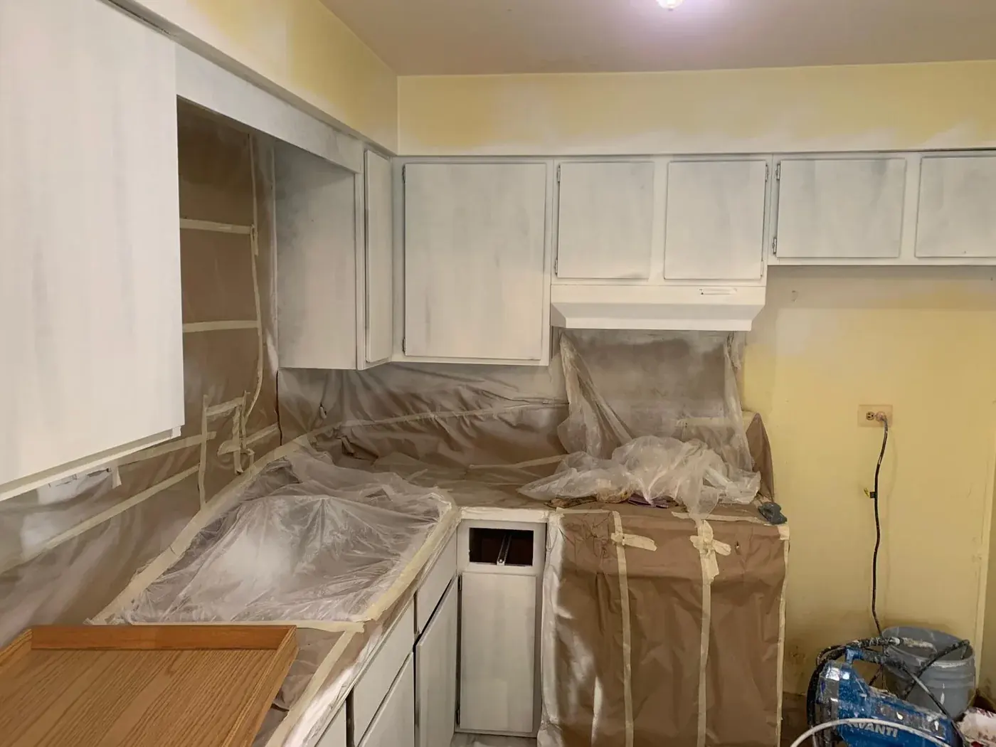Kitchen masked off and cabinet doors removed before spraying