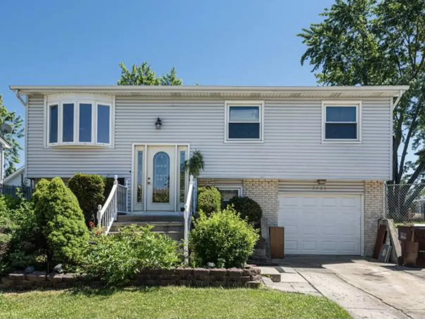 Two storey home before painting, tan siding with a white garage door