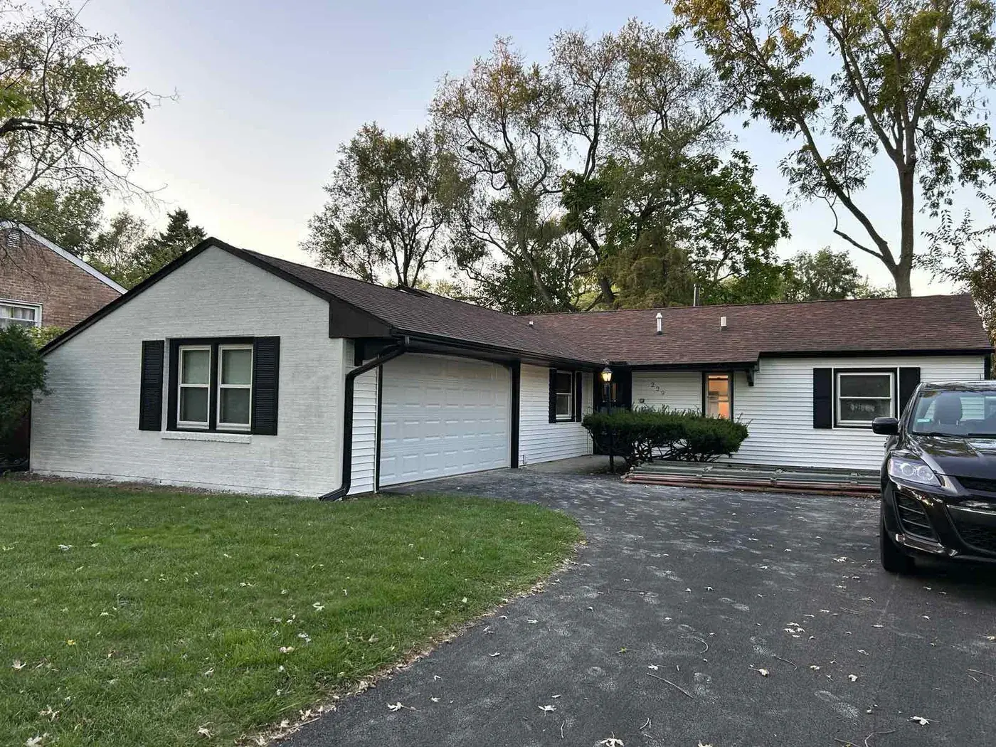 White painted brick ranch with black shutters and a dark front door