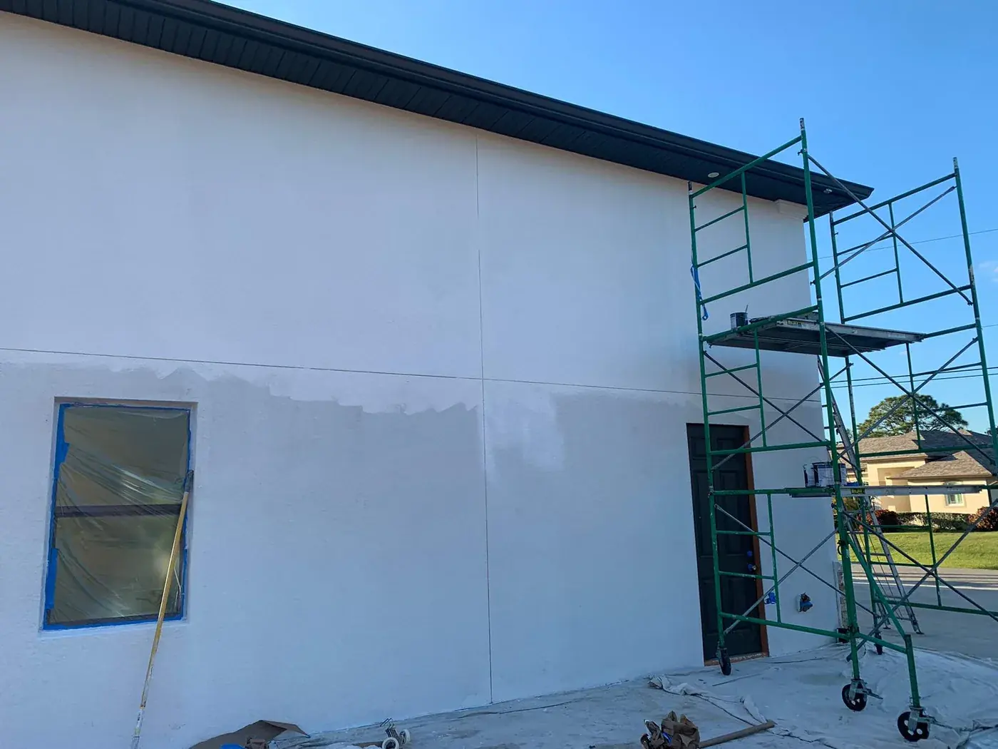 Painter spraying the exterior stucco wall of a Florida home from scaffolding