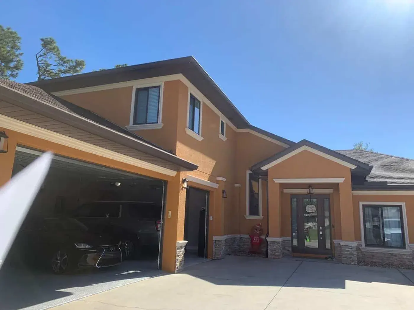 Two storey home in warm terracotta with white trim, stone base and an open garage
