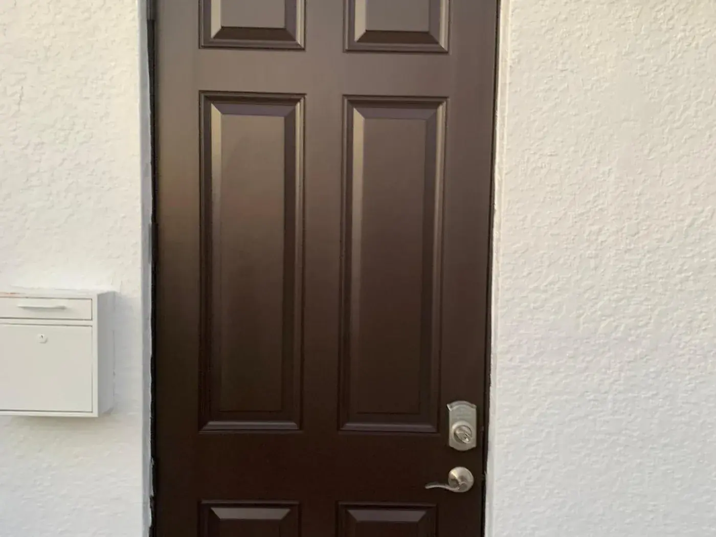 Dark brown front door set into a cream stucco wall
