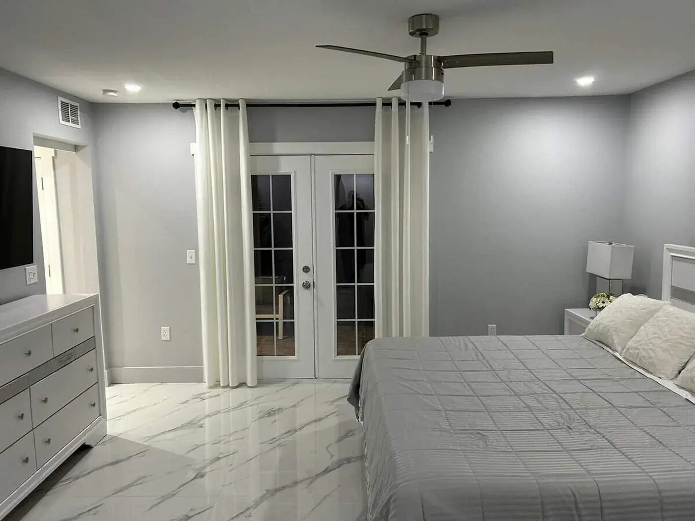 Bedroom repainted in soft grey with french doors onto the lanai and marble tile