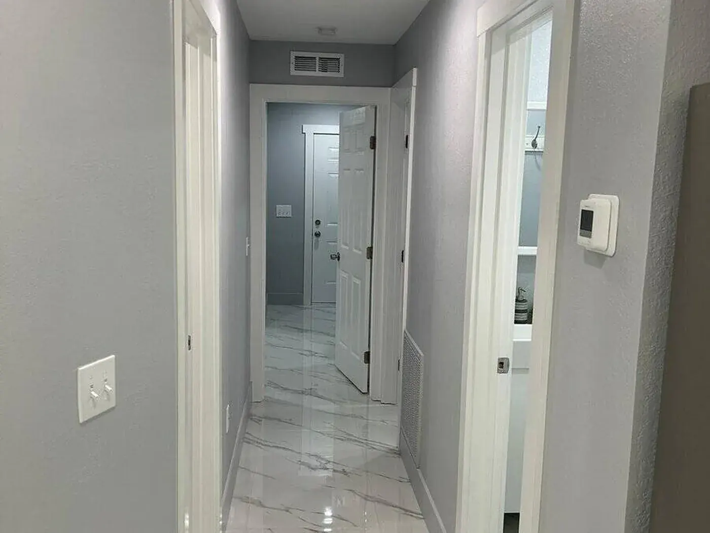 Hallway repainted in grey with marble tile running through to the back door