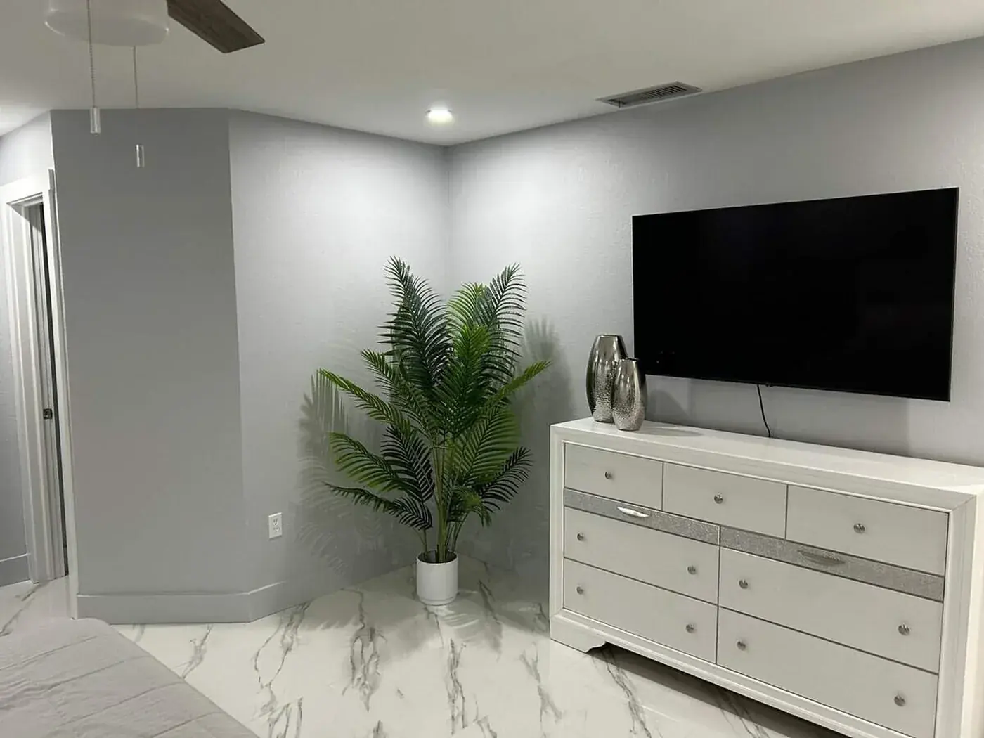 Bedroom corner after painting, soft grey walls against white trim and marble tile