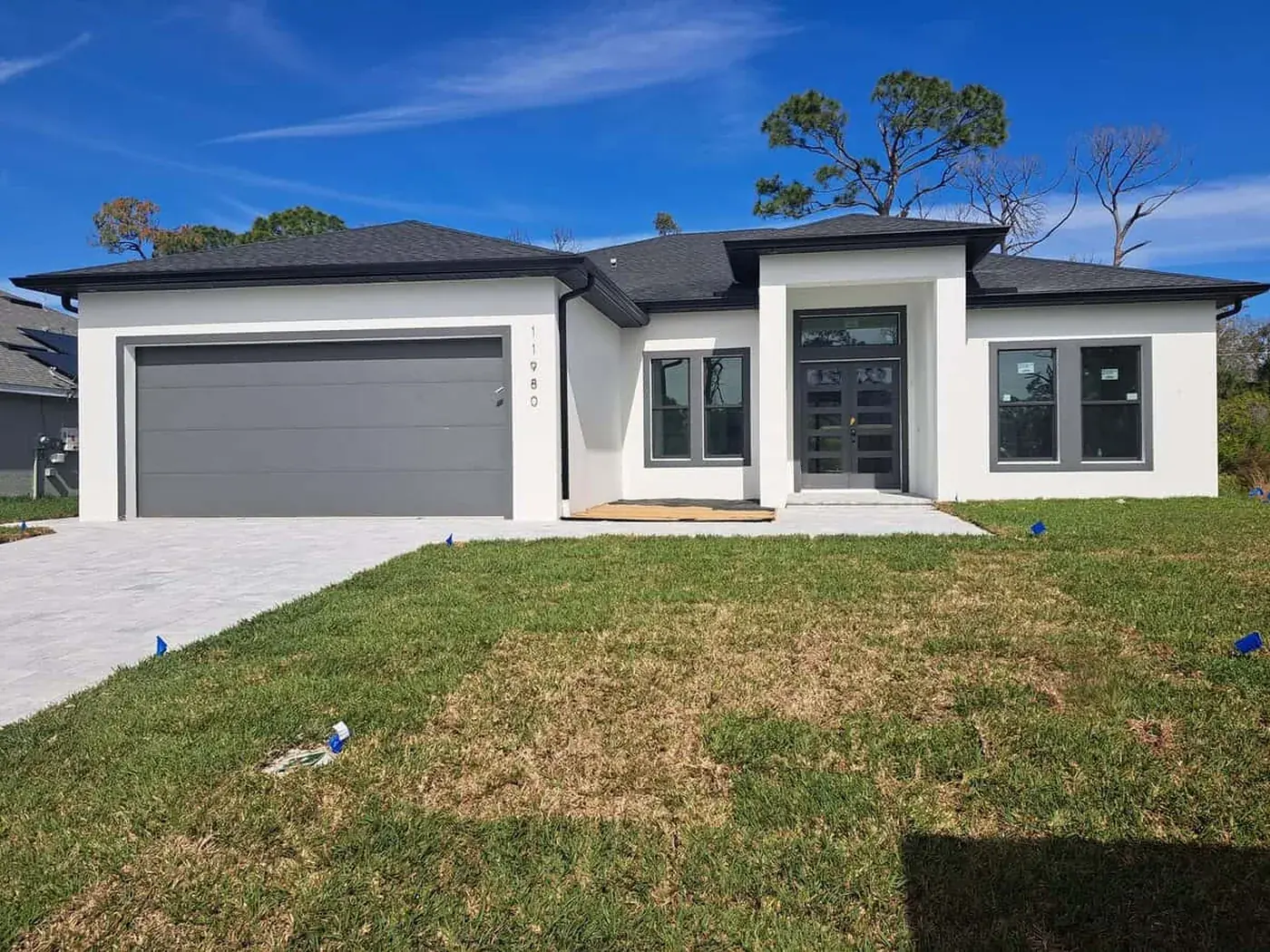 Finished Florida home in white with a grey garage door and dark window frames